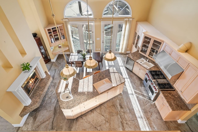 living room with a towering ceiling, sink, a high end fireplace, and french doors