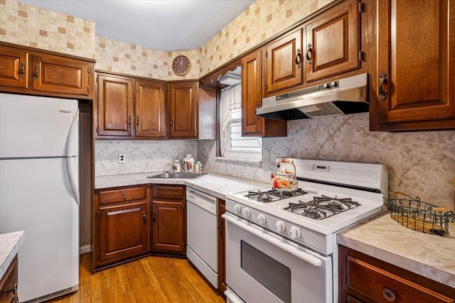 kitchen featuring light wood-type flooring, white appliances, backsplash, and sink