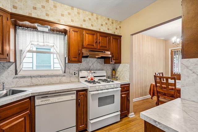 kitchen with sink, light hardwood / wood-style flooring, a notable chandelier, backsplash, and white appliances