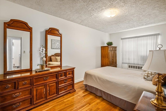 bedroom with a textured ceiling and light hardwood / wood-style flooring