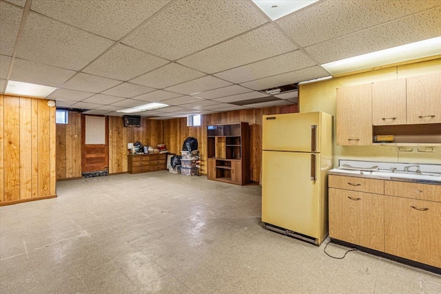 kitchen with sink, white refrigerator, a drop ceiling, and wood walls