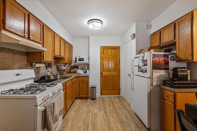 kitchen featuring white appliances, tasteful backsplash, light hardwood / wood-style flooring, and sink