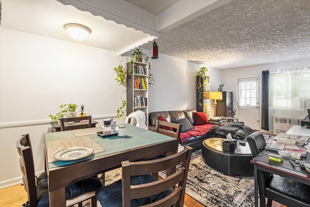 dining area featuring radiator heating unit, a textured ceiling, and hardwood / wood-style flooring