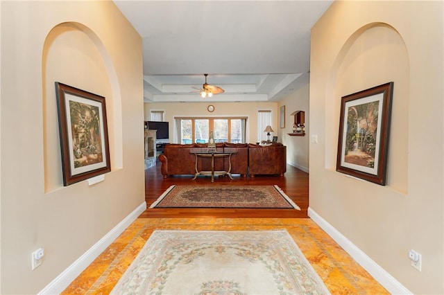 corridor featuring wood-type flooring and a tray ceiling