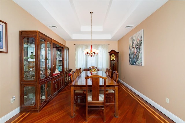 dining room with a raised ceiling, a chandelier, and dark hardwood / wood-style floors