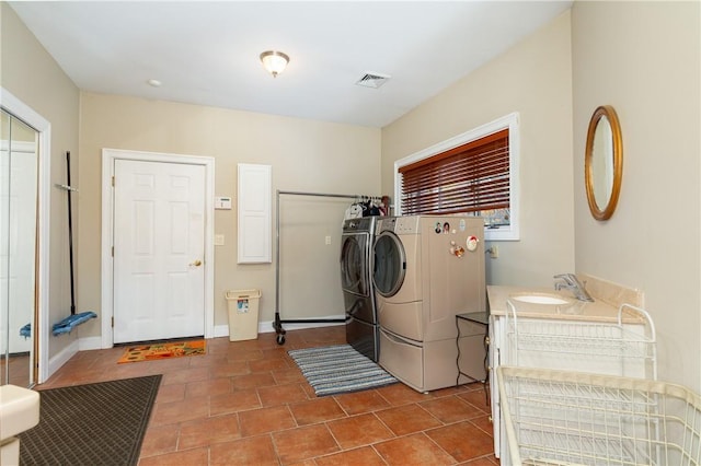 laundry area with tile patterned floors, washer and clothes dryer, and sink