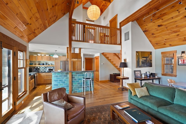 living area featuring high vaulted ceiling, wooden ceiling, visible vents, light wood-style floors, and stairway