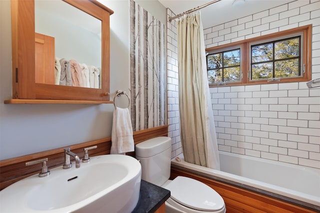 bathroom with toilet, shower / tub combo, and a sink