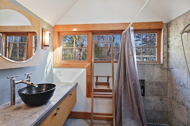 bathroom featuring lofted ceiling, a tile shower, and a healthy amount of sunlight