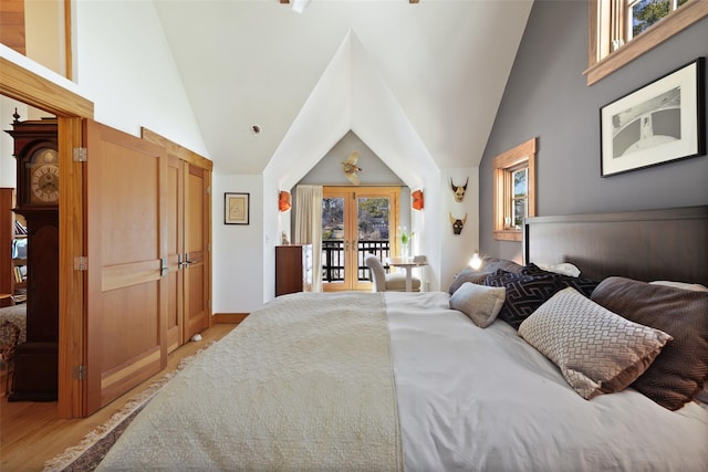 bedroom featuring light wood-style floors, access to outside, high vaulted ceiling, and french doors