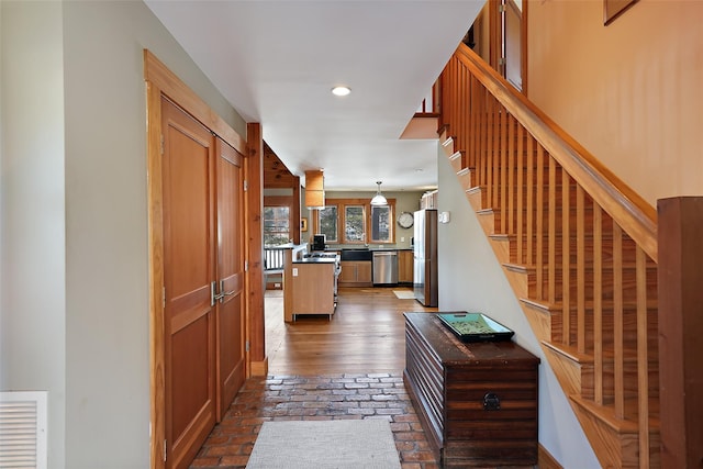 hall with brick floor, stairway, visible vents, and recessed lighting