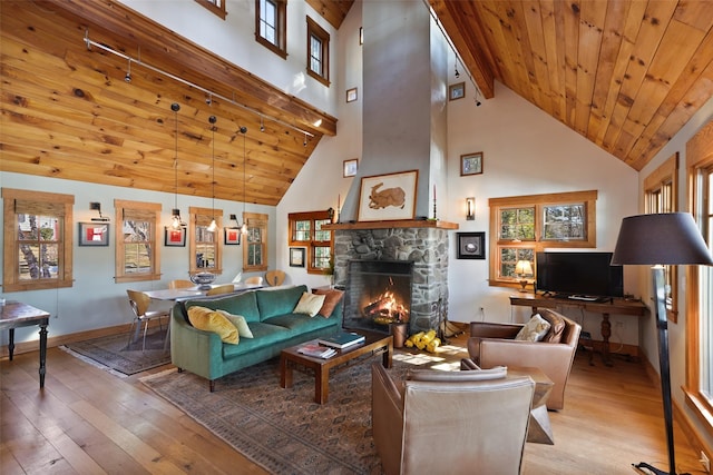 living area featuring a stone fireplace, high vaulted ceiling, wooden ceiling, baseboards, and hardwood / wood-style flooring