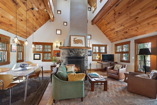 living room featuring a wealth of natural light, wood ceiling, wood finished floors, and a stone fireplace