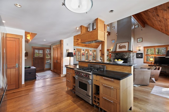 kitchen featuring dark countertops, open floor plan, high end stainless steel range oven, and light wood finished floors