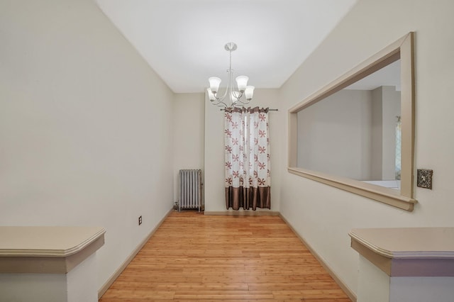 unfurnished dining area featuring radiator heating unit, a notable chandelier, and light wood-type flooring