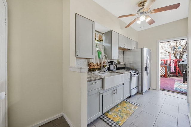 kitchen featuring gas range gas stove, sink, light tile patterned floors, and light stone counters