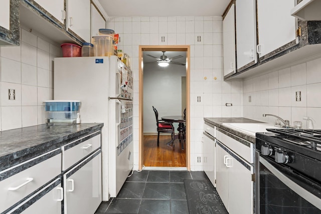 139-21 85th Dr Unit 3G, Briarwood, NY 11435 - kitchen with tile walls, freestanding refrigerator, dark tile patterned flooring, black gas stove, and ceiling fan