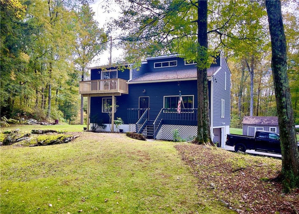 rear view of property with a yard, a balcony, an outdoor structure, and a garage