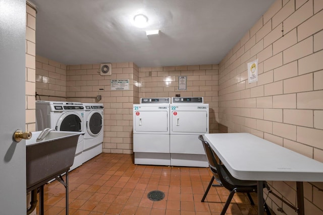 laundry area with separate washer and dryer and tile walls