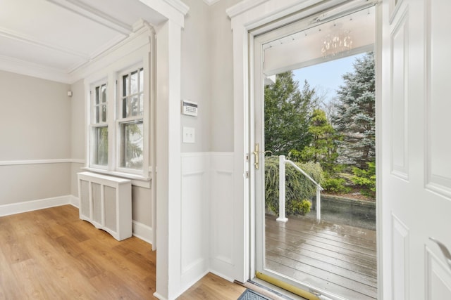 entryway featuring radiator, crown molding, light hardwood / wood-style flooring, and a healthy amount of sunlight