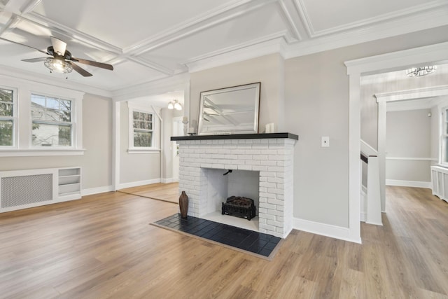 living room with radiator, coffered ceiling, ceiling fan, crown molding, and a fireplace