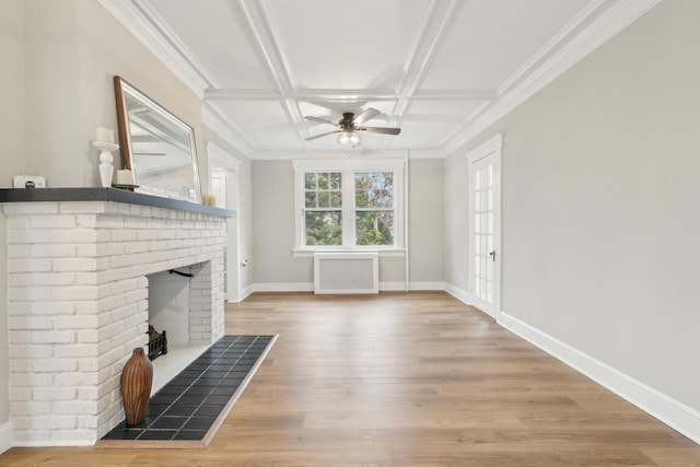 unfurnished living room featuring hardwood / wood-style floors, coffered ceiling, a brick fireplace, ceiling fan, and radiator heating unit