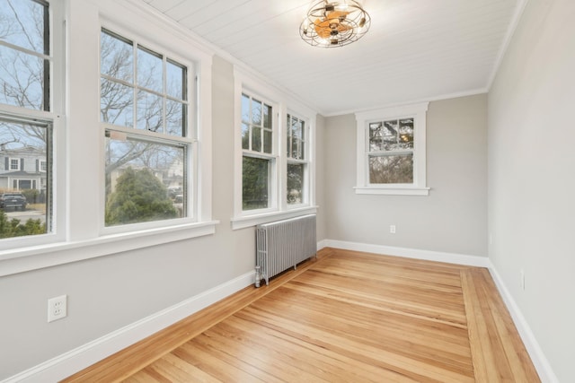 unfurnished room featuring wood-type flooring, radiator heating unit, and ornamental molding