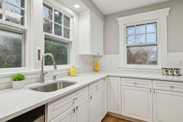 kitchen with tasteful backsplash, white cabinetry, sink, and dishwasher