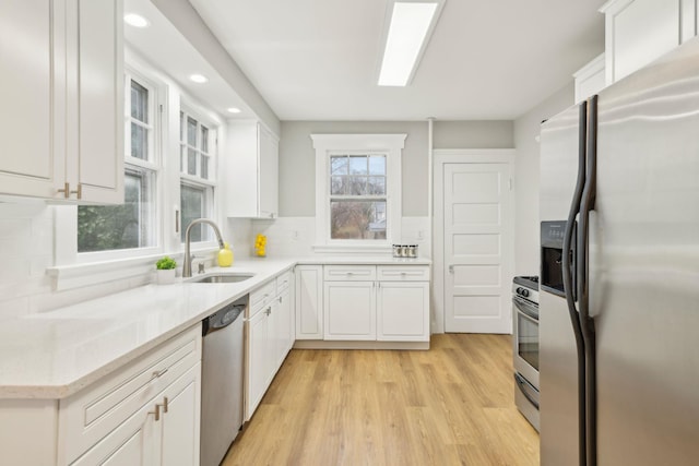 kitchen with sink, stainless steel appliances, light hardwood / wood-style floors, decorative backsplash, and white cabinets