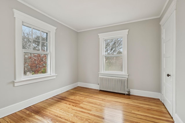 unfurnished bedroom featuring multiple windows, light hardwood / wood-style flooring, radiator, and ornamental molding