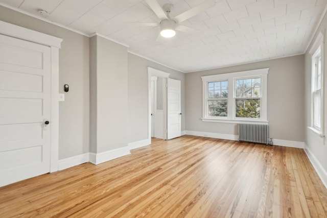 empty room featuring light wood-type flooring, radiator, crown molding, and ceiling fan