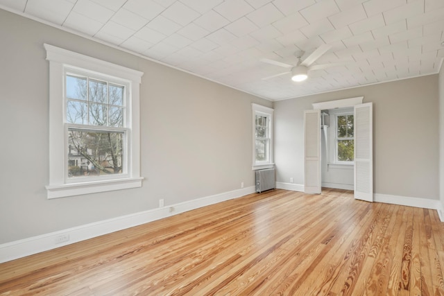 unfurnished room featuring ceiling fan, light wood-type flooring, radiator heating unit, and ornamental molding