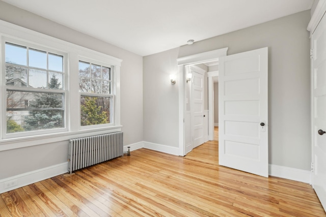 spare room featuring radiator and light wood-type flooring