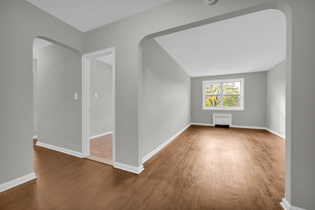 spare room featuring radiator and dark hardwood / wood-style floors