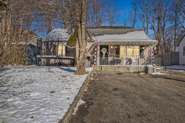 snow covered property featuring covered porch and a trampoline