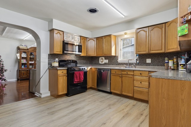 kitchen featuring light wood-type flooring, stainless steel appliances, backsplash, and sink