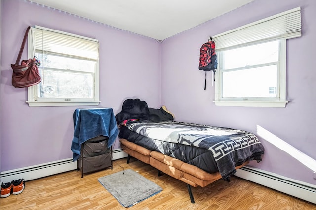 bedroom with light wood-type flooring and a baseboard heating unit