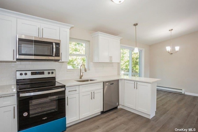 kitchen featuring appliances with stainless steel finishes, a wealth of natural light, a baseboard heating unit, sink, and white cabinetry