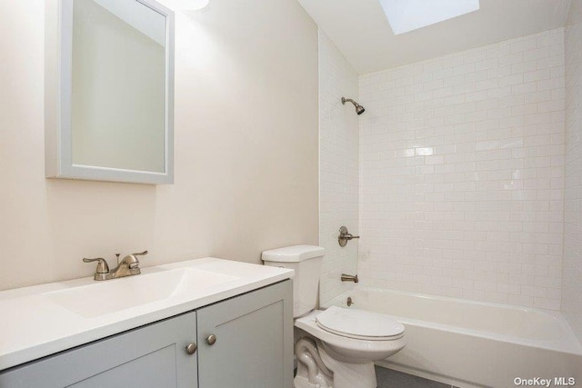 full bathroom featuring vanity, a skylight, toilet, and tiled shower / bath combo