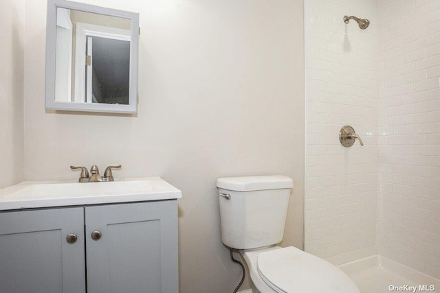 bathroom featuring tiled shower, vanity, and toilet