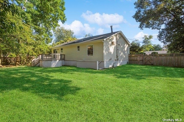 rear view of property featuring a lawn and a deck