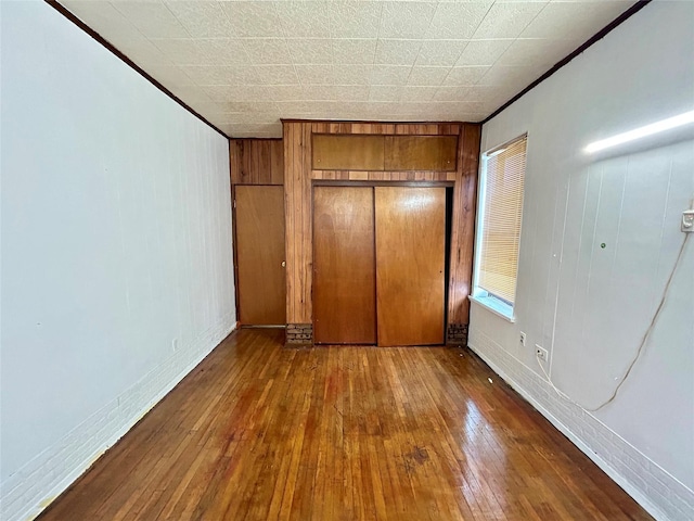 unfurnished bedroom featuring a closet, ornamental molding, and hardwood / wood-style flooring