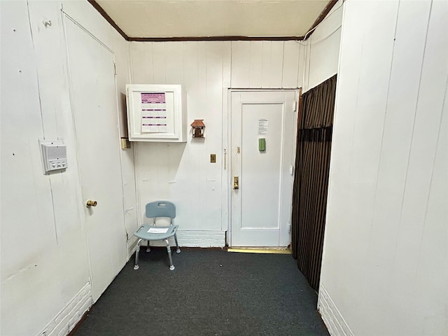 hall featuring wood walls and dark carpet