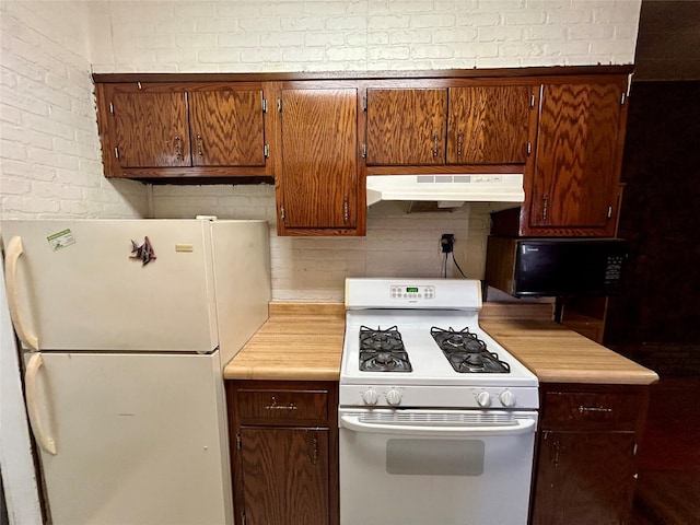 kitchen with white appliances and brick wall