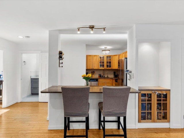 kitchen featuring stainless steel appliances, kitchen peninsula, a kitchen bar, sink, and tasteful backsplash