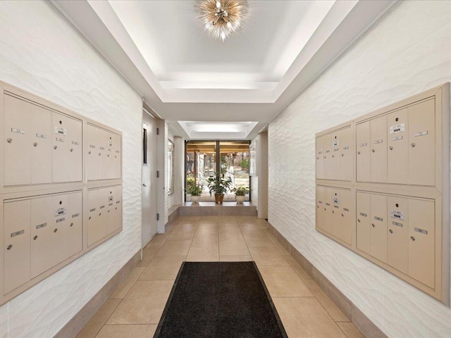 hallway with a mail area, light tile patterned floors, and a tray ceiling