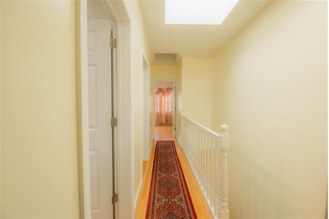 hallway with wood-type flooring and a skylight