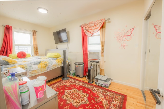 bedroom featuring light wood-type flooring, radiator, and cooling unit