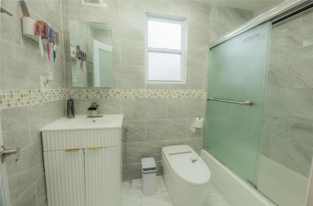 full bathroom featuring vanity, toilet, enclosed tub / shower combo, and tile walls