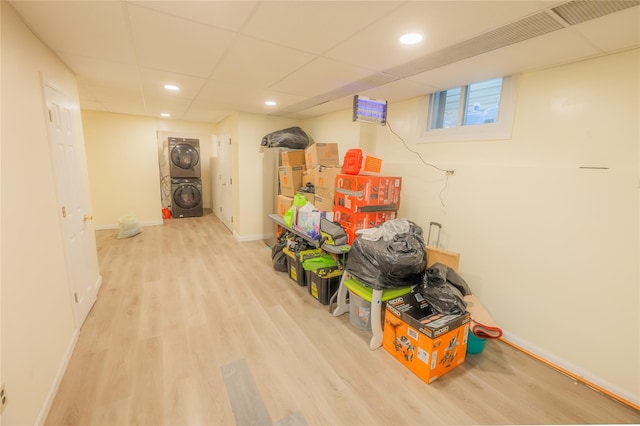 basement featuring a paneled ceiling, wood-type flooring, and stacked washer / drying machine